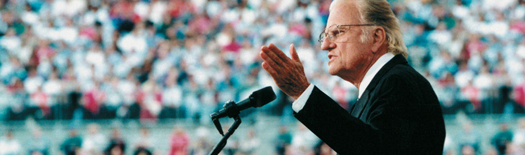 Rev. Billy Graham preaching to a large stadium audience