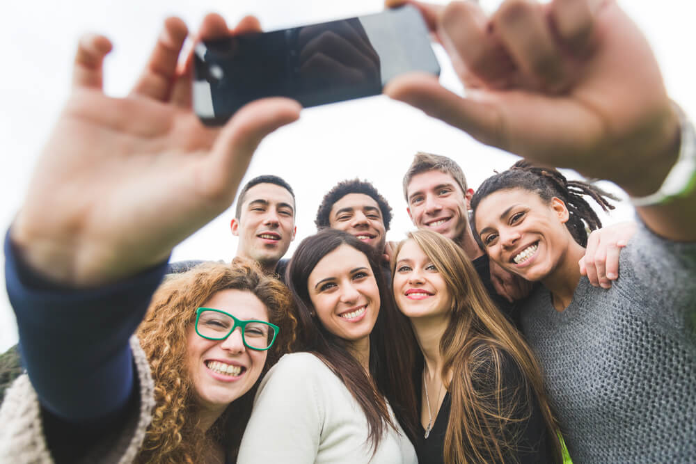 Image of four young women and three young men taking a group selfie