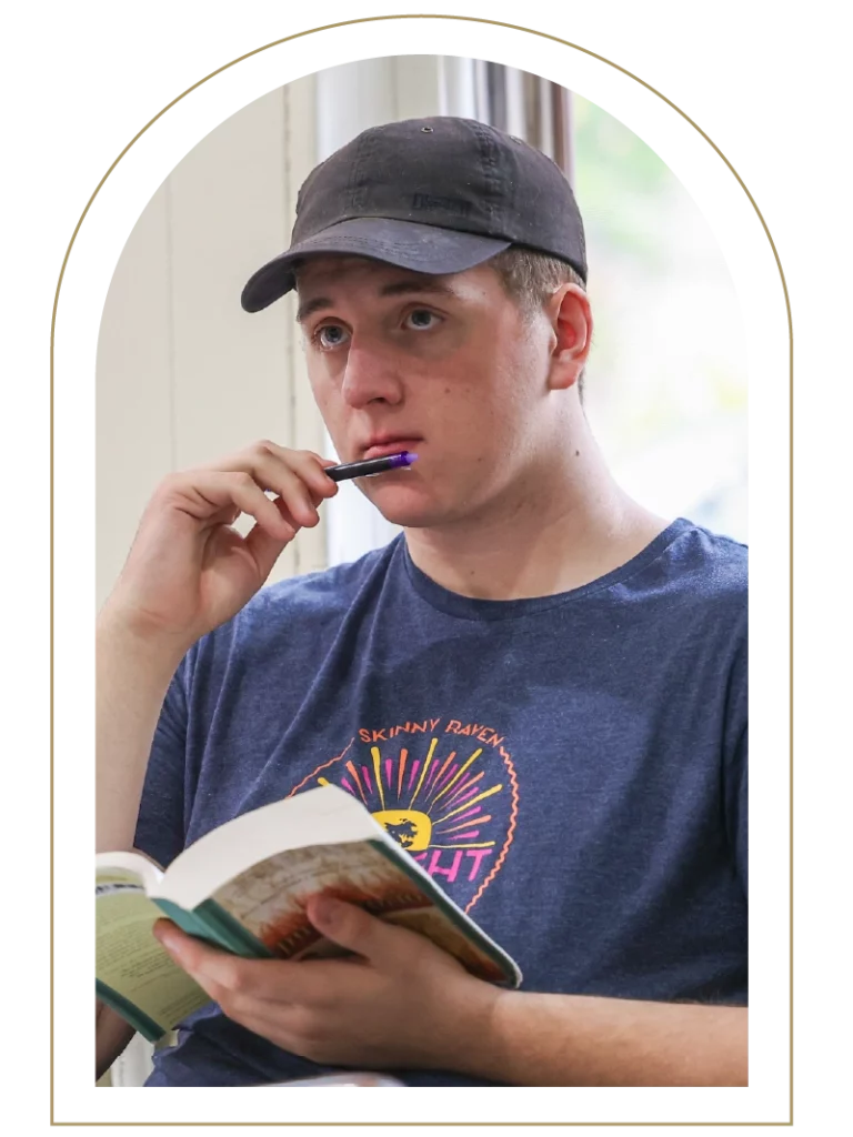 Young man sitting looking pensive while holding a book