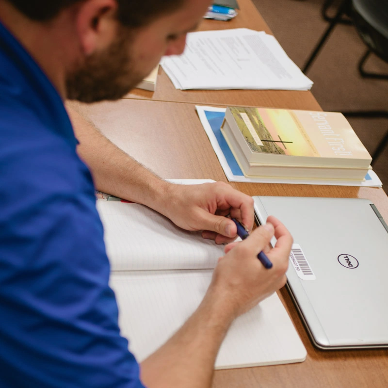 A man holds a pen and looks down at it
