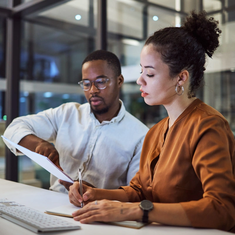 A man and woman look at a stack of papers