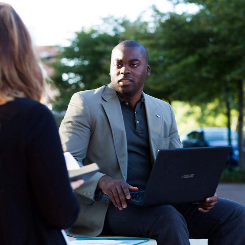 A man holding a laptop looks at a woman
