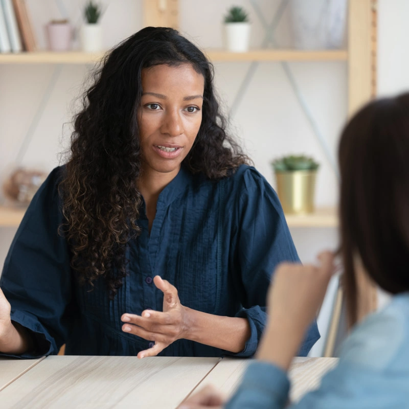 A woman wearing a blue shirt looks at someone in the foreground who is out of focus