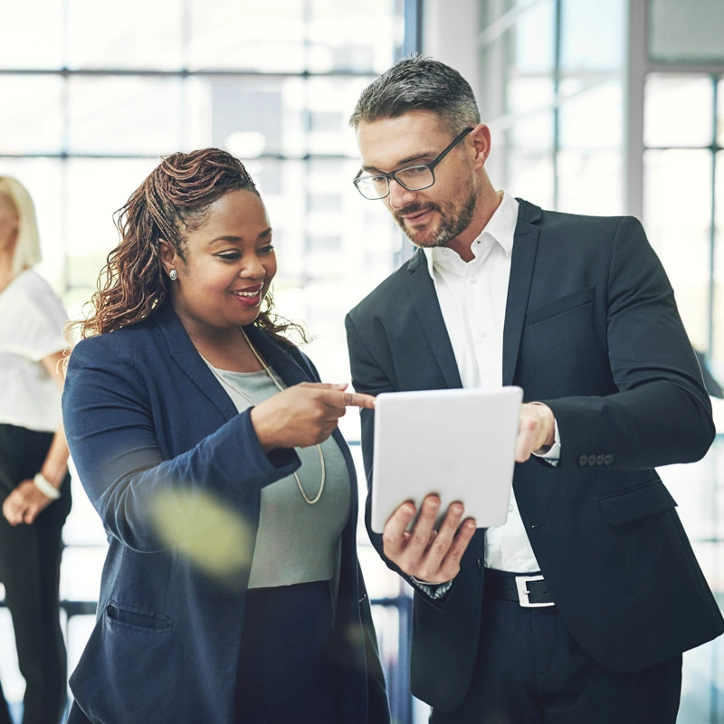 A man and woman look at a tablet and talk