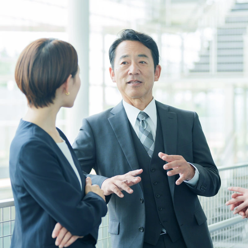 A man and woman dressed in formal business clothes speak to one another