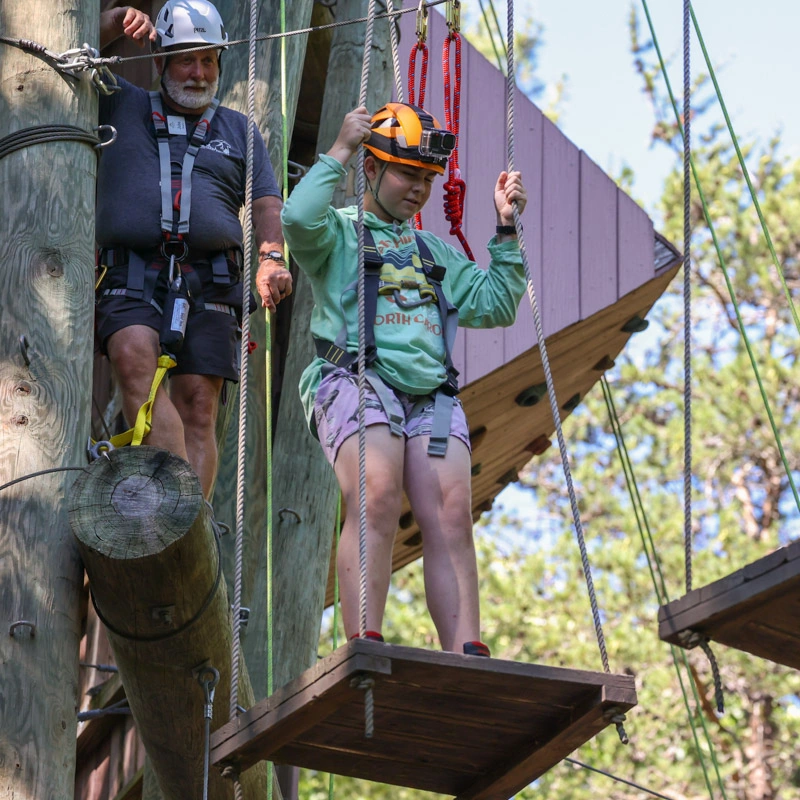 A young woman navigates a high ropes course