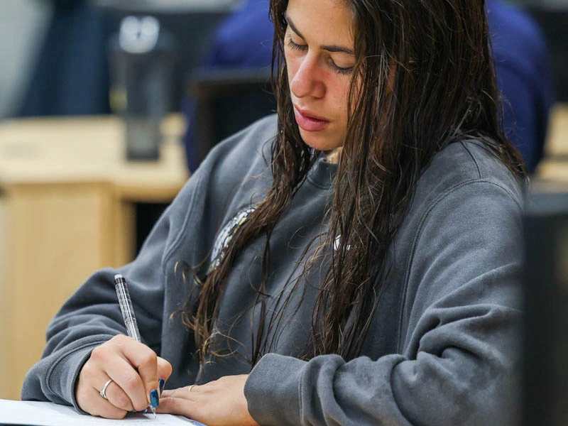 A young woman looks down and writes in a notebook
