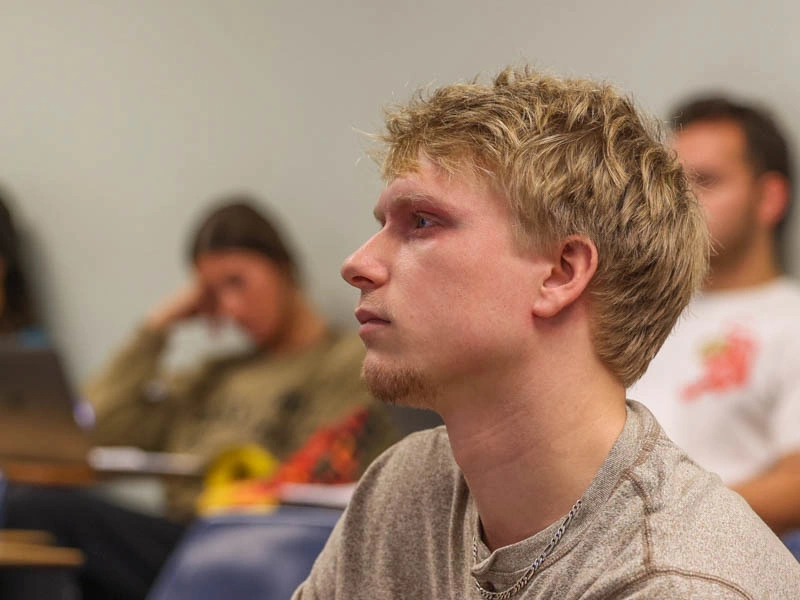 A young man sits and looks to the left