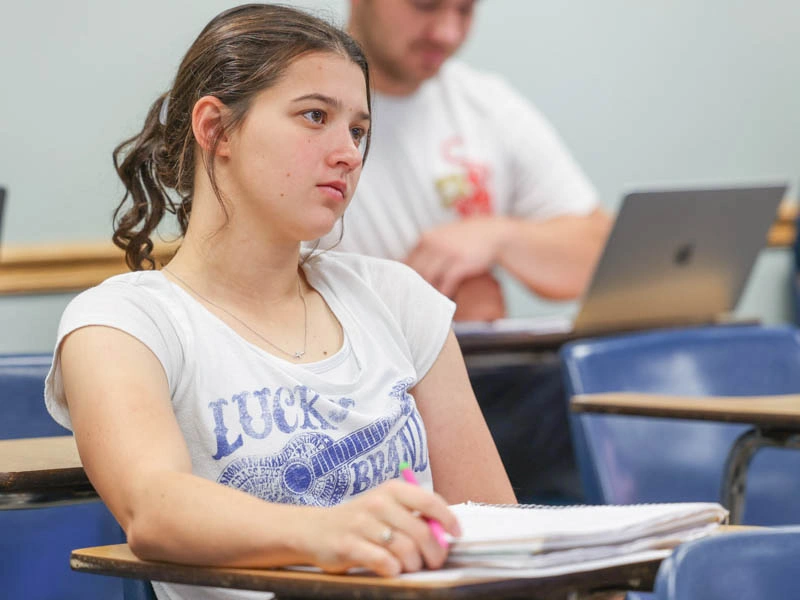 A young woman sits at a college desk