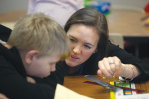 Caroline Clark shows a young boy something on a table