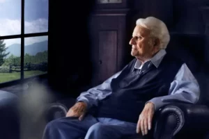 Billy Graham sitting in a chair, looking out a window