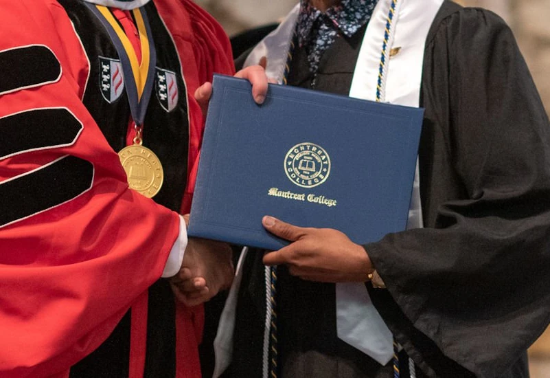 President Maurer hands a graduate their degree at college commencement
