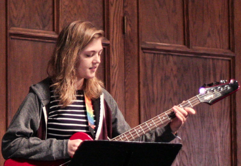 A young woman plays a guitar in Graham Chapel