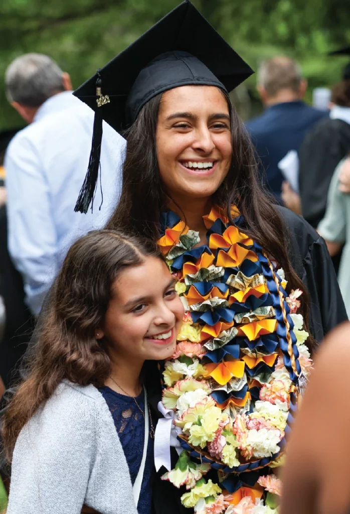 A graduate smiles with a younger sister or daughter