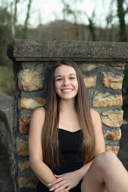 Hannah Potter sits in front of a brick tower and smiles
