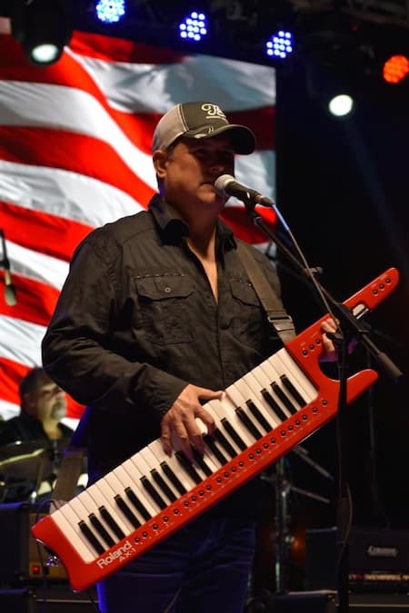 Tim McDonald stands on stage playing a musical instrument