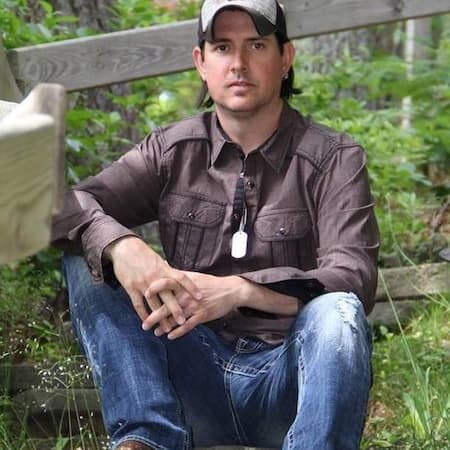 Tim McDonald sits in front of a fence