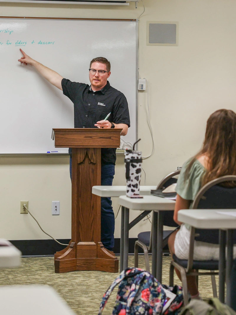 A professor points at a white board