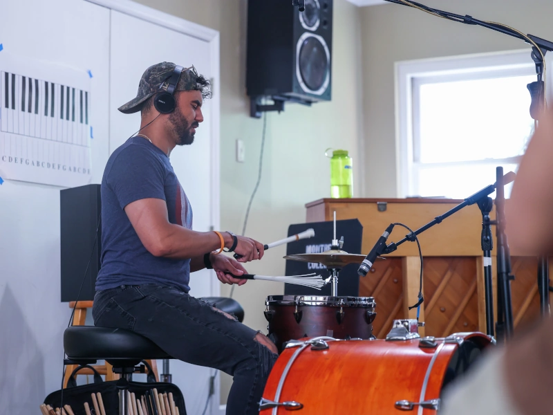 A man with a beard plays drums