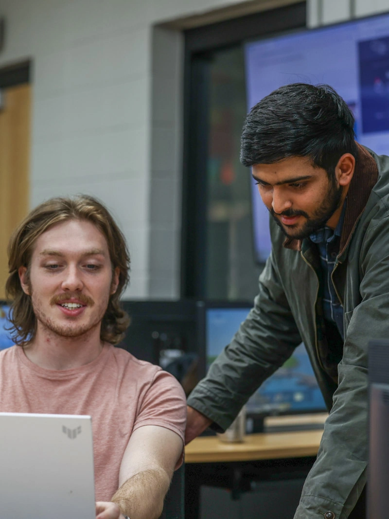 Two young men look down at a computer screen