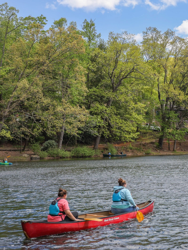 Two young women canoe down a river