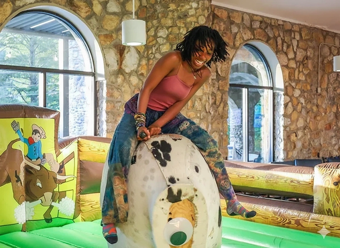 A student riding an inflated imaginary animal in a bounce house