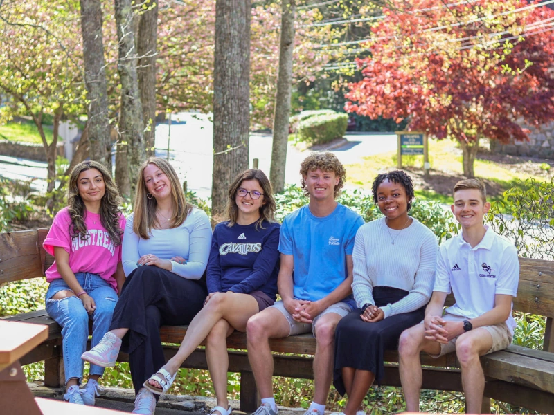 Smiling students sitting on a bench outside